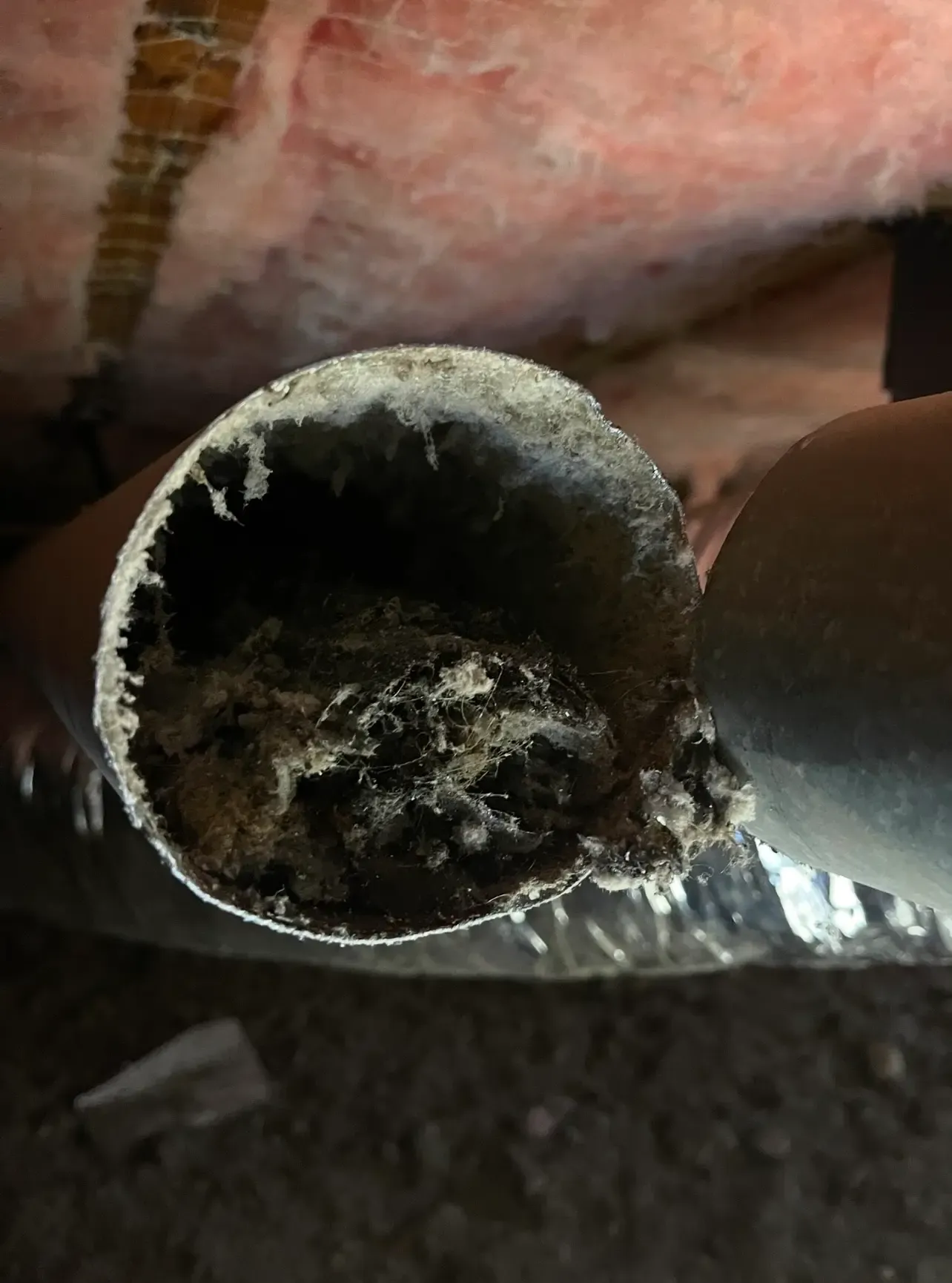 A dryer vent duct packed with built-up lint before cleaning