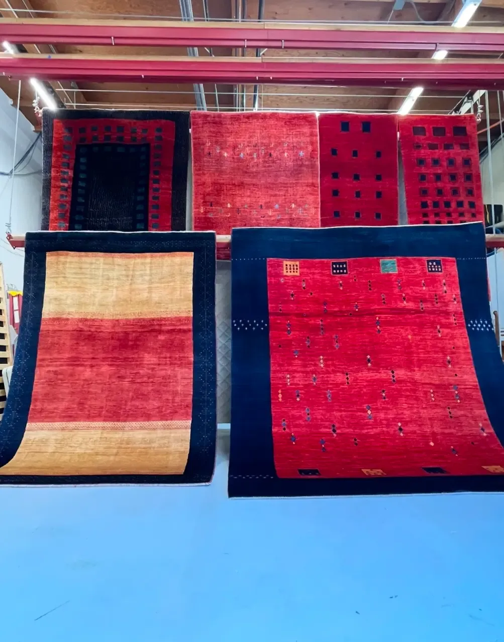 Wool rugs hanging on racks inside the Simply Clean Care rug facility